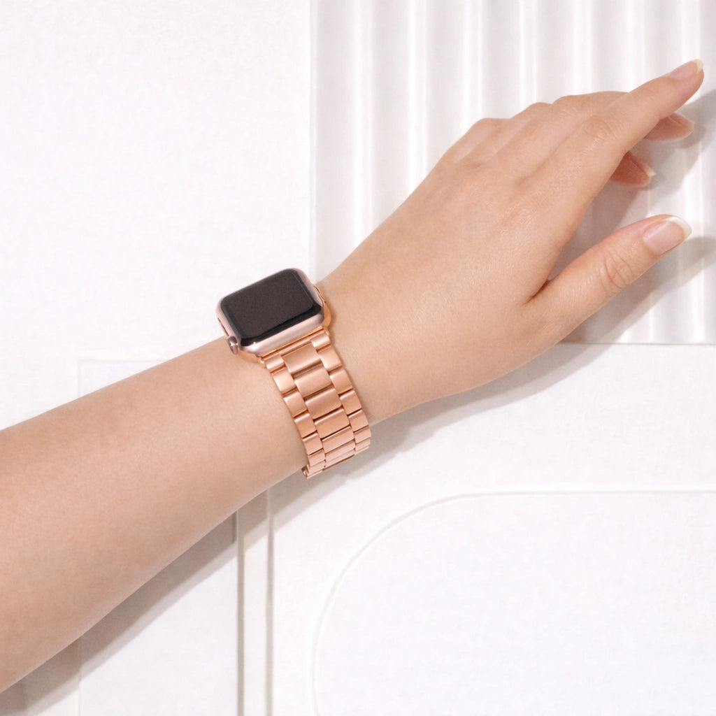 Rose gold stainless steel Apple Watch strap with metal link bracelet design displayed on white stand
