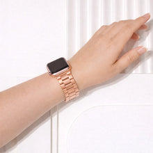 Rose gold stainless steel Apple Watch strap with metal link bracelet design displayed on white stand