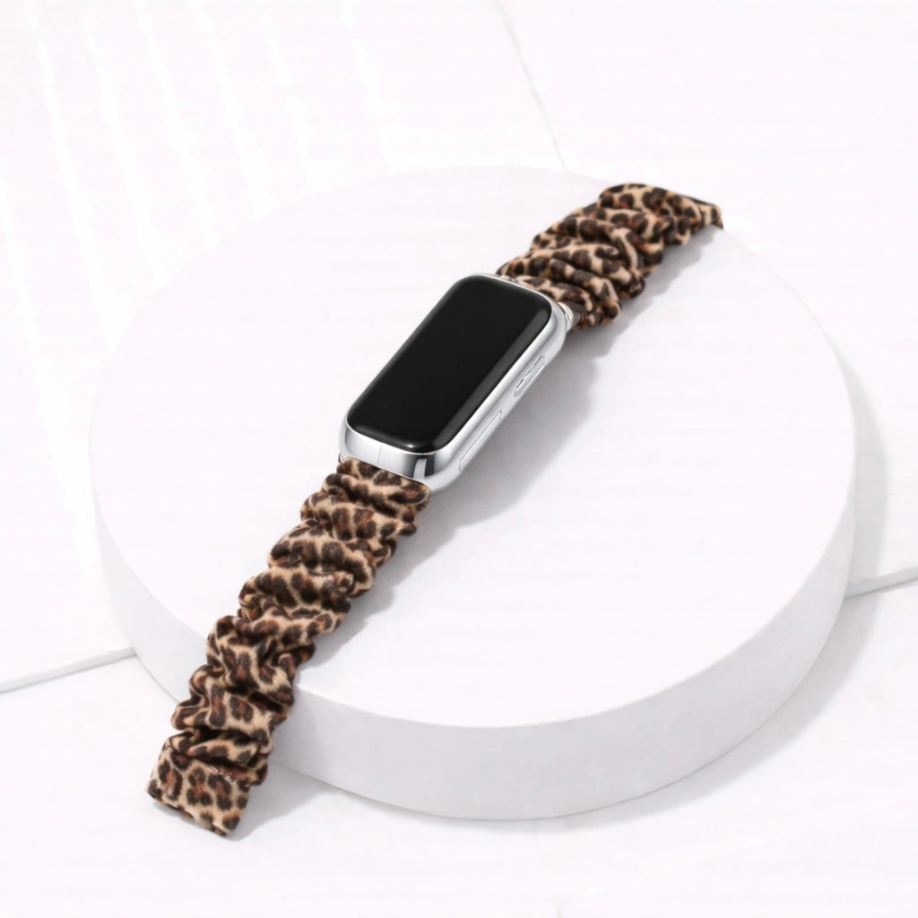 Leopard print scrunchie band for Fitbit Luxe on white display stand