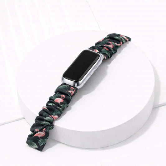 Flamingo print scrunchie band for Fitbit Luxe, attached to device on a white display stand. 