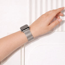 Silver metal Apple Watch band worn on the wrist against a light textured background