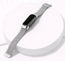 Silver Milanese watch band for Fitbit Inspire 3 displayed on a stand