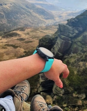 Wearing a smartwatch with a teal strap while hiking in the mountains