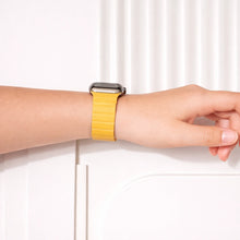 Yellow leather strap for Apple Watch worn on the wrist.